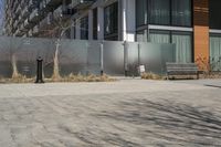 there is an empty walkway with a bench beside it in the background that also has an apartment building