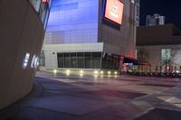 an empty, empty walkway that leads into the buildings and the light is on at night