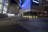 an empty, empty walkway that leads into the buildings and the light is on at night