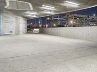 an empty concrete walkway outside with a parking garage below it with a skateboard resting on the ledge of it