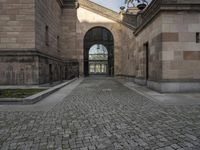 a horse statue and archway at the end of an empty walkway in front of the palace