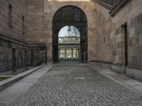 a horse statue and archway at the end of an empty walkway in front of the palace