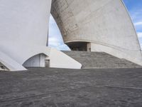 an empty walkway leading to a large white building with steps up to it's top