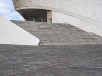 an empty walkway leading to a large white building with steps up to it's top