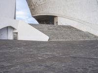 an empty walkway leading to a large white building with steps up to it's top