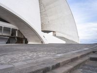 an empty walkway leading to a large white building with steps up to it's top