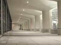 an empty walkway in a very modern building with the lights on and outside windows open