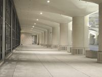 an empty walkway in a very modern building with the lights on and outside windows open