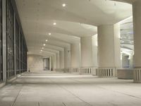 an empty walkway in a very modern building with the lights on and outside windows open