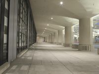 an empty walkway in a very modern building with the lights on and outside windows open