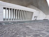 an empty walkway leads to a building with huge white columns that form a structure of arches