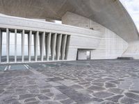 an empty walkway leads to a building with huge white columns that form a structure of arches