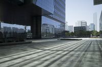 an empty walkway with a reflection in it and some buildings behind it, next to a street