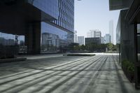 an empty walkway with a reflection in it and some buildings behind it, next to a street