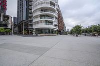 an empty paved concrete walkway next to tall buildings and parked cars in a downtown area