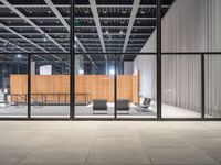 an empty warehouse with glass doors and chairs on the side of it with no people sitting inside