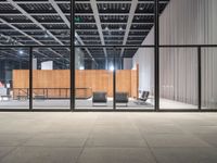 an empty warehouse with glass doors and chairs on the side of it with no people sitting inside