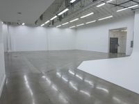 an empty white building with many lights coming from inside the building and floors with large rectangulars