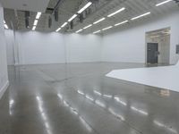 an empty white building with many lights coming from inside the building and floors with large rectangulars