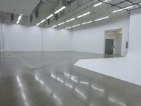 an empty white building with many lights coming from inside the building and floors with large rectangulars