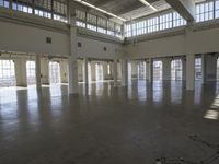 an empty empty warehouse with no roof, lots of windows and light coming in from high ceilings