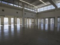 an empty empty warehouse with no roof, lots of windows and light coming in from high ceilings