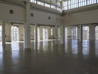 an empty empty warehouse with no roof, lots of windows and light coming in from high ceilings