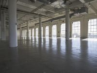 an empty empty warehouse with no roof, lots of windows and light coming in from high ceilings