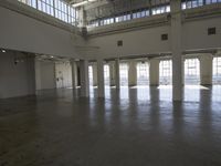 an empty empty warehouse with no roof, lots of windows and light coming in from high ceilings