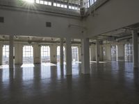 an empty empty warehouse with no roof, lots of windows and light coming in from high ceilings