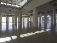 an empty empty warehouse with no roof, lots of windows and light coming in from high ceilings