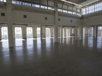 an empty empty warehouse with no roof, lots of windows and light coming in from high ceilings