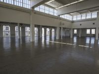 an empty empty warehouse with no roof, lots of windows and light coming in from high ceilings