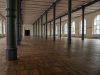 an empty warehouse like structure with wooden floors and arches in the middle of the room