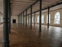 an empty warehouse like structure with wooden floors and arches in the middle of the room