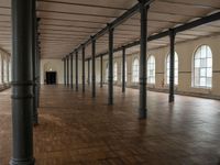 an empty warehouse like structure with wooden floors and arches in the middle of the room