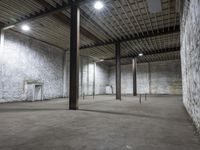 an empty warehouse with exposed ceilings and concrete walls and beams holding up electrical equipment and lighting