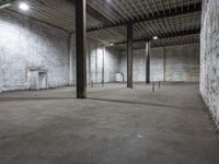 an empty warehouse with exposed ceilings and concrete walls and beams holding up electrical equipment and lighting