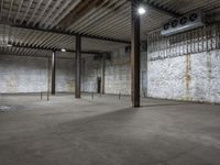 an empty warehouse with exposed ceilings and concrete walls and beams holding up electrical equipment and lighting