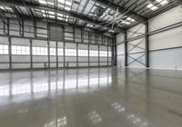 an empty warehouse is very high with no walls and light pouring in the floor to flood