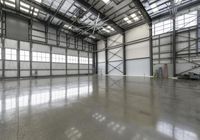 an empty warehouse is very high with no walls and light pouring in the floor to flood