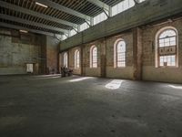 an empty warehouse with lots of windows and some machinery on the ground and a person in a cart