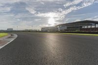 the sun shining on a racetrack that is empty and well maintained off to the side