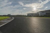 the sun shining on a racetrack that is empty and well maintained off to the side