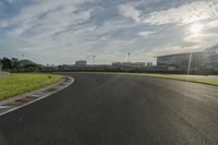 the sun shining on a racetrack that is empty and well maintained off to the side