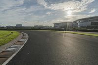 the sun shining on a racetrack that is empty and well maintained off to the side