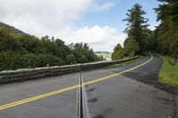 the road is winding and empty in this photograph, with green trees to the side