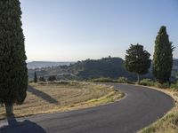 an empty, winding, winding road surrounded by trees and hills in a rural area