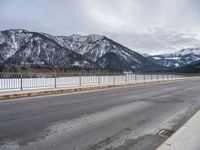 an empty mountain road in winter with snow on the ground and trees near by,