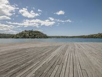 the wooden pier is empty with water and trees in the distance from which there is no one